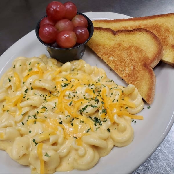 Creamy macaroni and cheese with shredded cheddar and parsley, served with grapes and toasted bread.