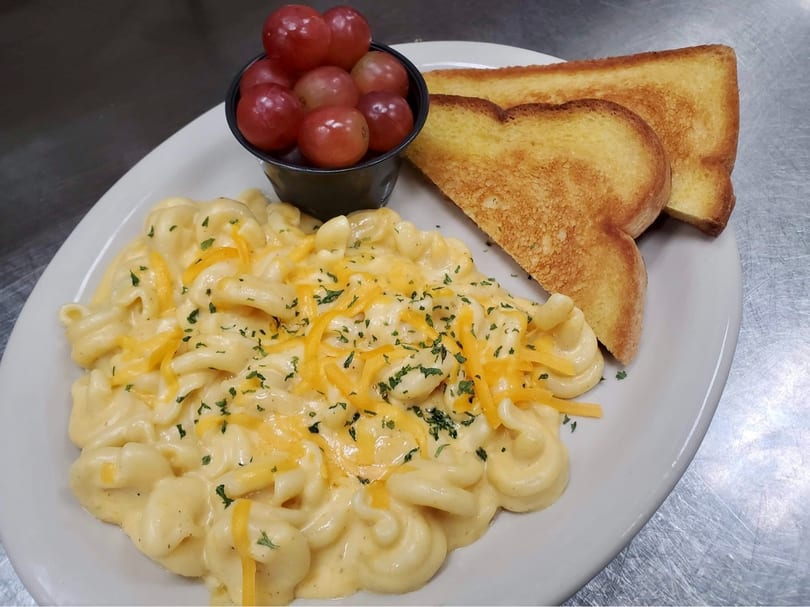 Creamy macaroni and cheese with shredded cheddar and parsley, served with grapes and toasted bread.