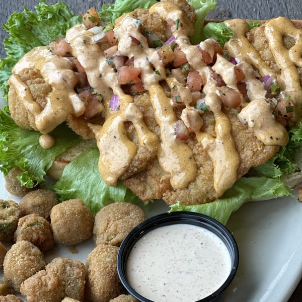Fried chicken sandwich with lettuce, pico de gallo, and sauce, served with fried okra and ranch.
